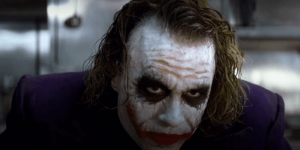 joker looksup at someone in a meeting in the dark knight